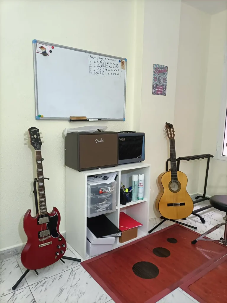 aula de guitarra para clases con una guitarra clasica y otra electrica y una pizarra en las palmas